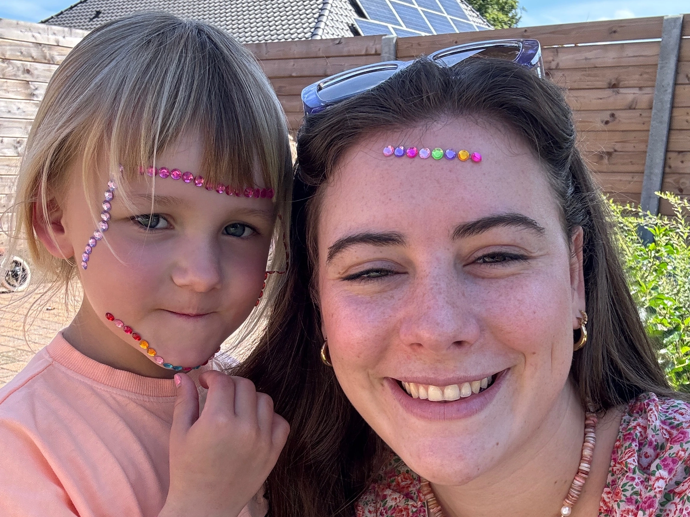 Vrouw en meisje buiten met kleurrijke stickers op hun gezichten.