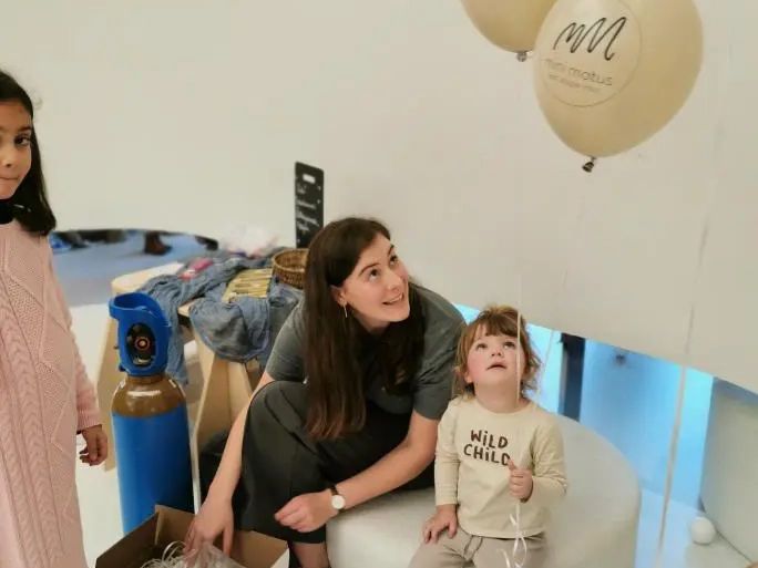 Vrouw en kind met ballon tijdens een binnenevenement.