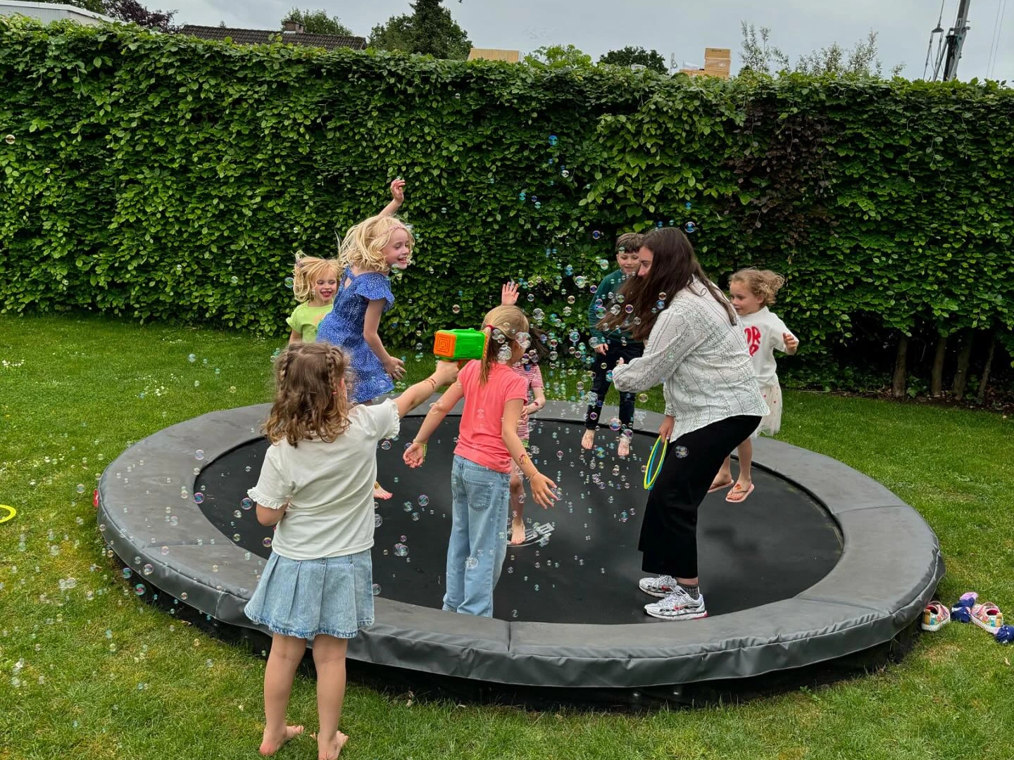 Kinderen spelen met bellen op een trampoline in de tuin.